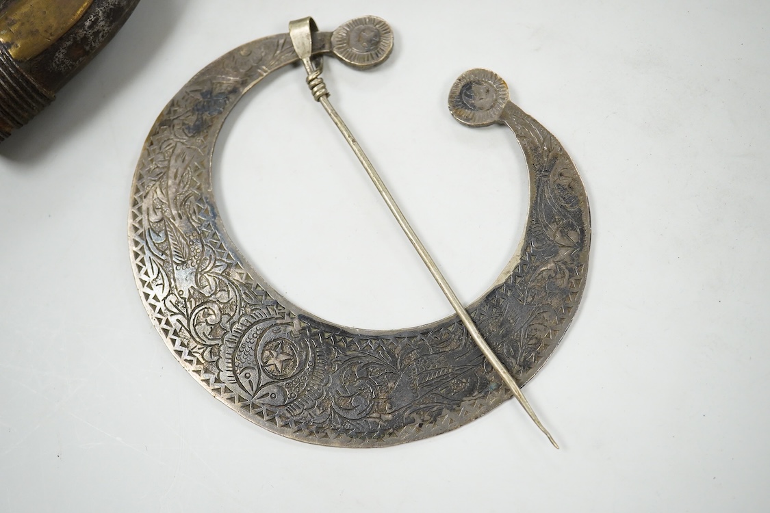 A niello work belt buckle, 21cm wide, an Arab white metal cloak brooch and a powder flask